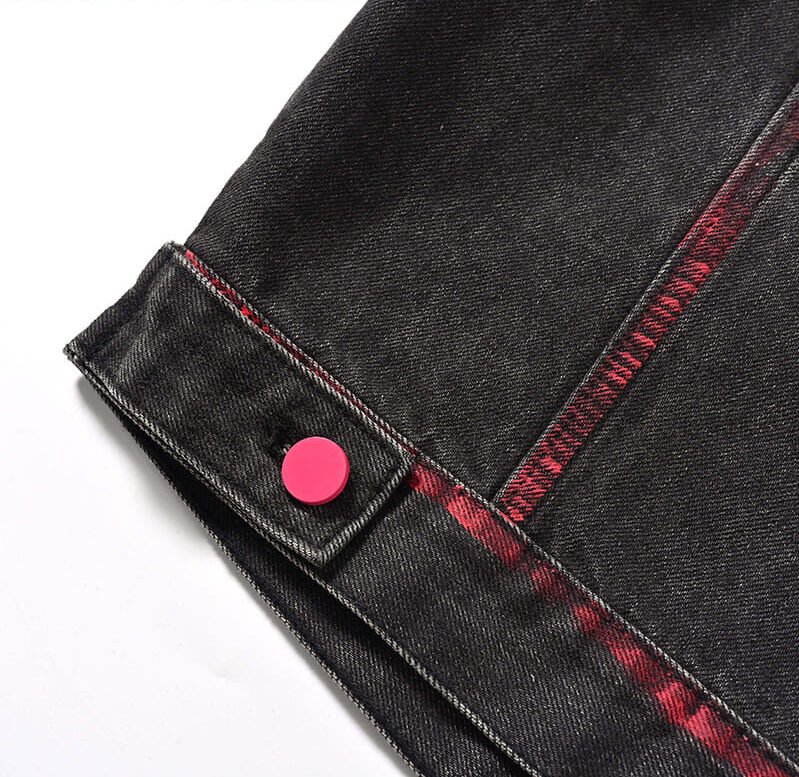 cropped washed‑black denim jacket rear‑hem close‑up, matte pink round snap fastener, red hand‑spray graffiti detailing, heavy twill denim weave, rear hem fabric texture detail shot