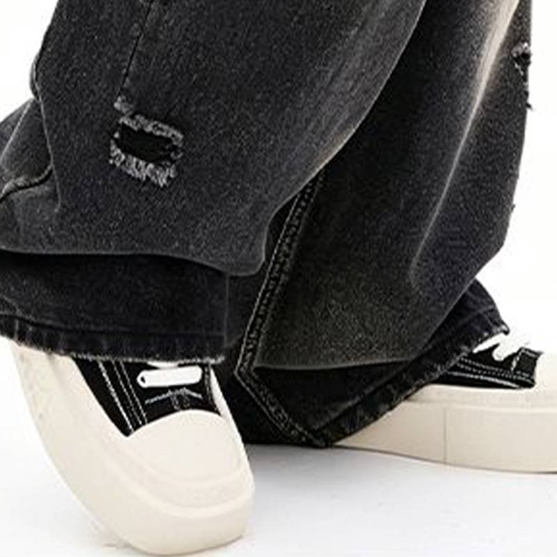 hem close-up of custom heavy wash destroyed relaxed fitting denim pants, frayed rip and fabric texture