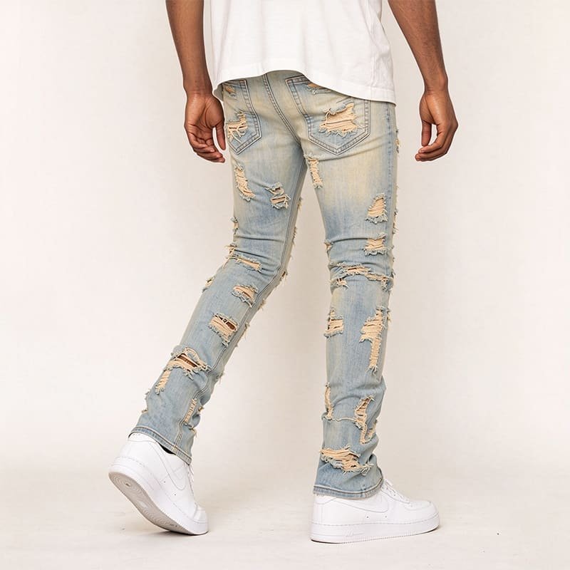 side rear angled model shot, sand washed ripped denim showing elastic skinny fitting fabric drape