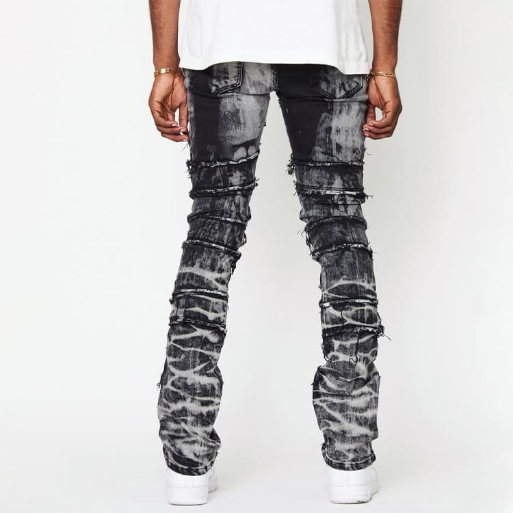 back view of spliced raw edge panel denim pants, horizontal leg panel splicing and exposed raw seam edge details